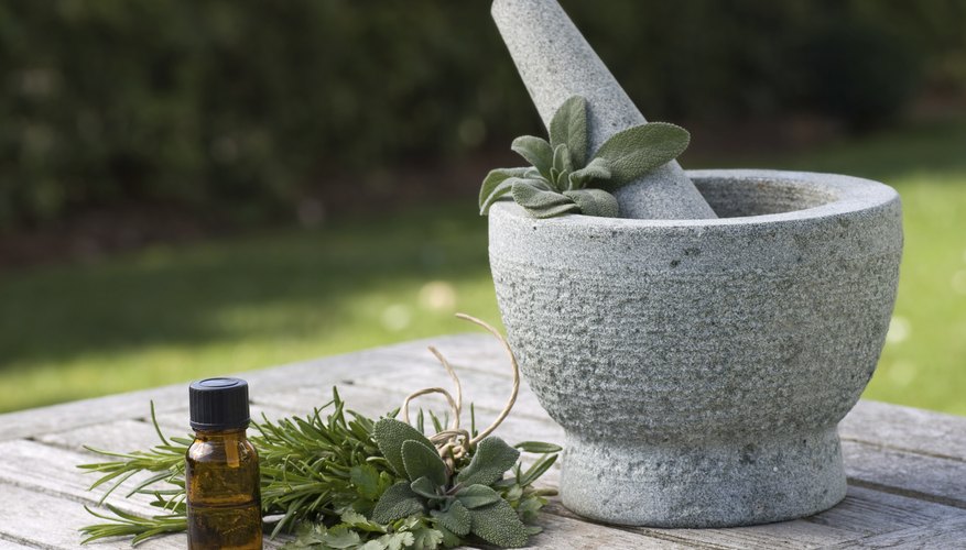 A bottle of sage oil and a mortar and pestle on an outside table A bottle of sage oil and a mortar and pestle on an outside table