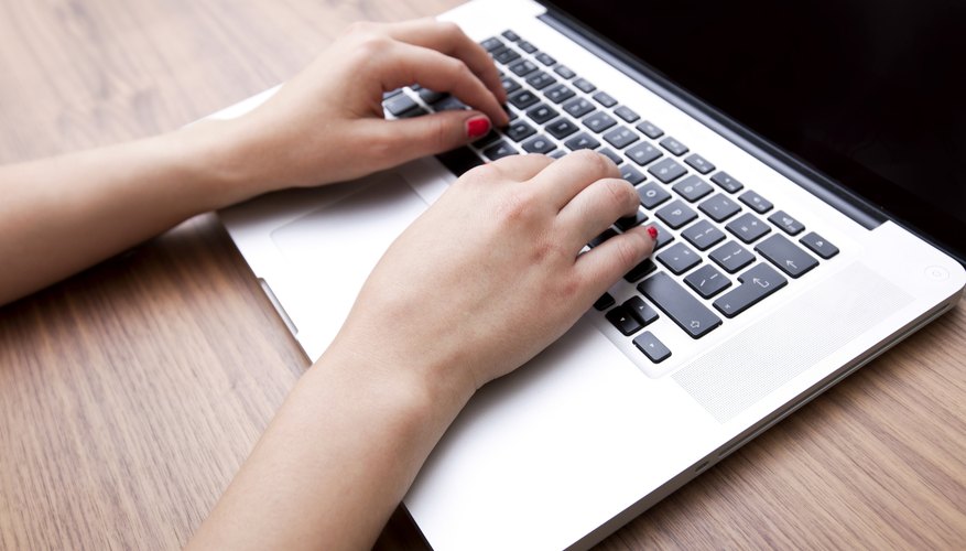 Close-up of businesswoman's hands using laptop at table