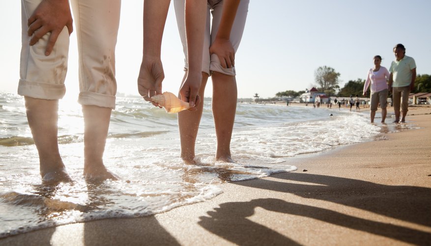 Photo Credit: XiXinXing/iStock/Getty Images Group of people searching for shells on beach