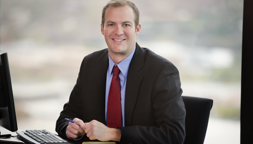 Photo Credit: Ben Blankenburg/iStock/Getty Images A software consultant smiling at an office desk.