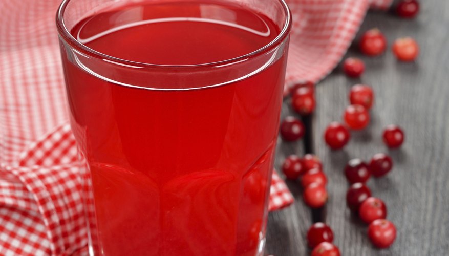A glass of cranberry juice on a table with cranberries A glass of cranberry juice on a table with cranberries