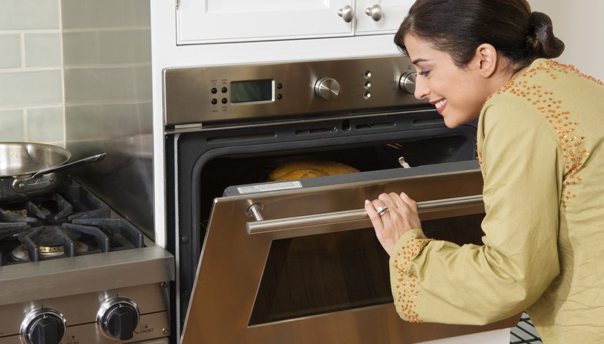 Woman checking on Thanksgiving turkey in oven