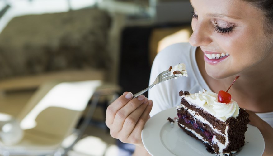 A woman is eating a large slice of chocolate cake. A woman is eating a large slice of chocolate cake.