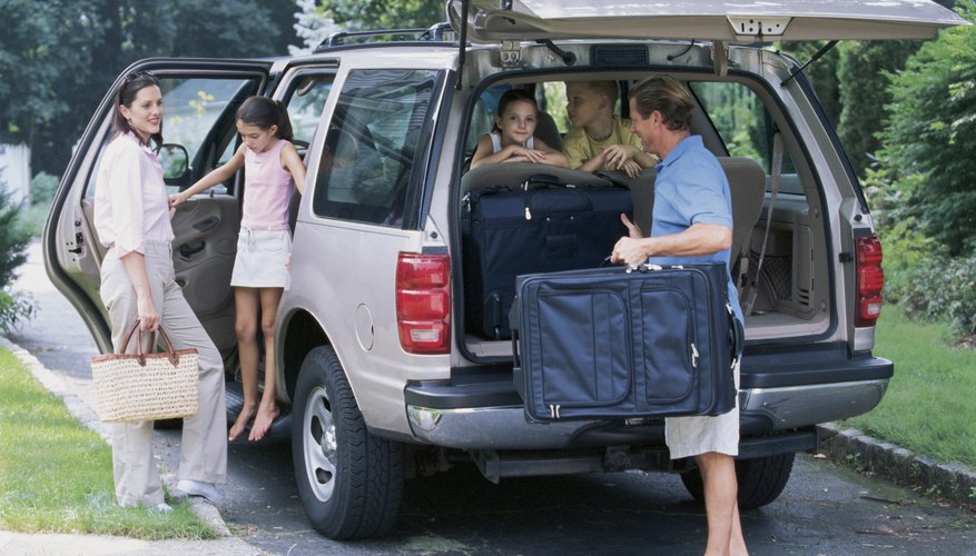 Family packing suitcases into SUV