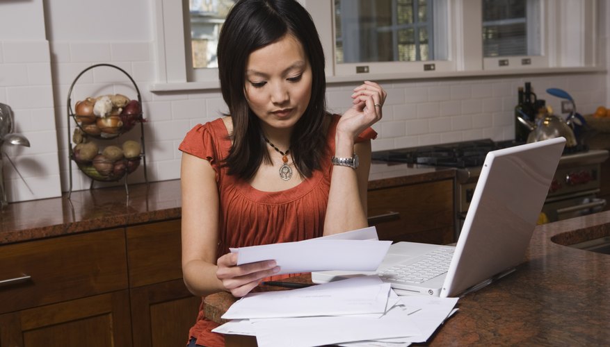 Woman looking at paperwork next to laptop