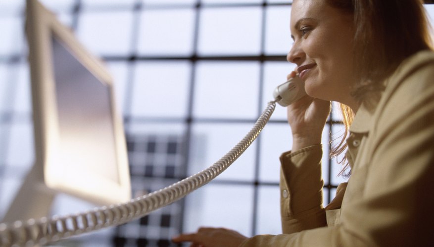 Businesswoman talking on a telephone sitting in front of a computer monitor