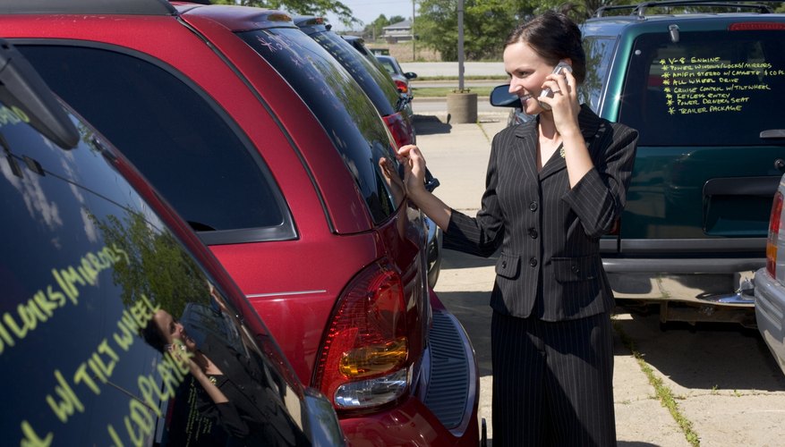 Saleswoman on cell phone in used car lot