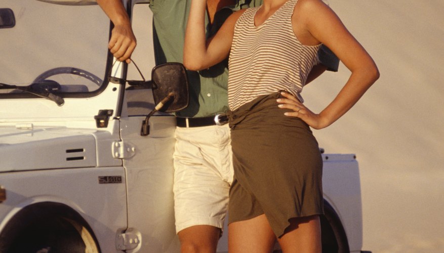 Couple standing on sand with off-road vehicle