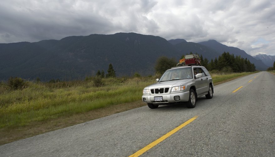 Canada, British Columbia, Pitt Meadows, couple driving sports utility vehicle along rural road