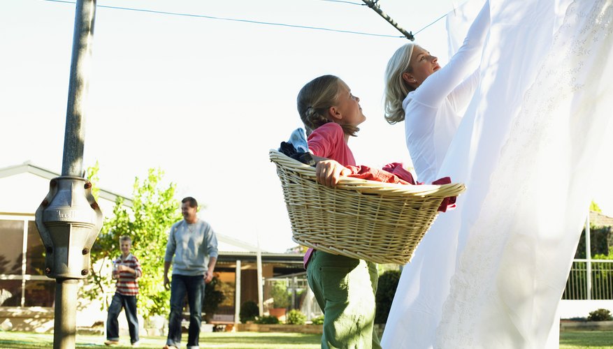 Girl helping her mother hang up sheets Girl helping her mother hang up sheets