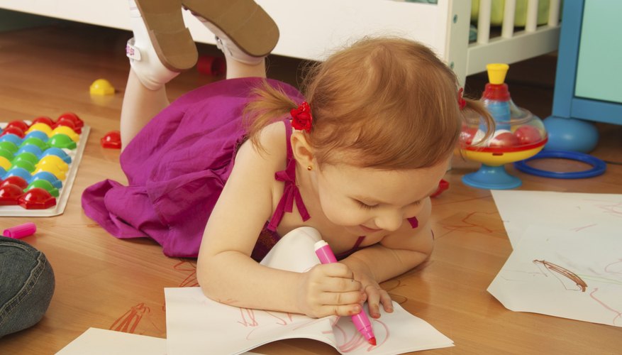 A two-year-old girl uses paper and washable markers. A two-year-old girl uses paper and washable markers.