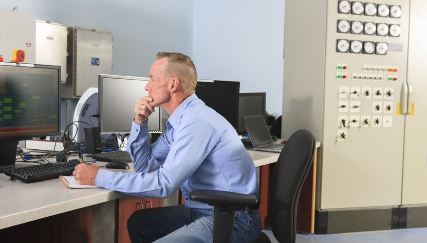 Engineer at electric power plant control room watching management displays