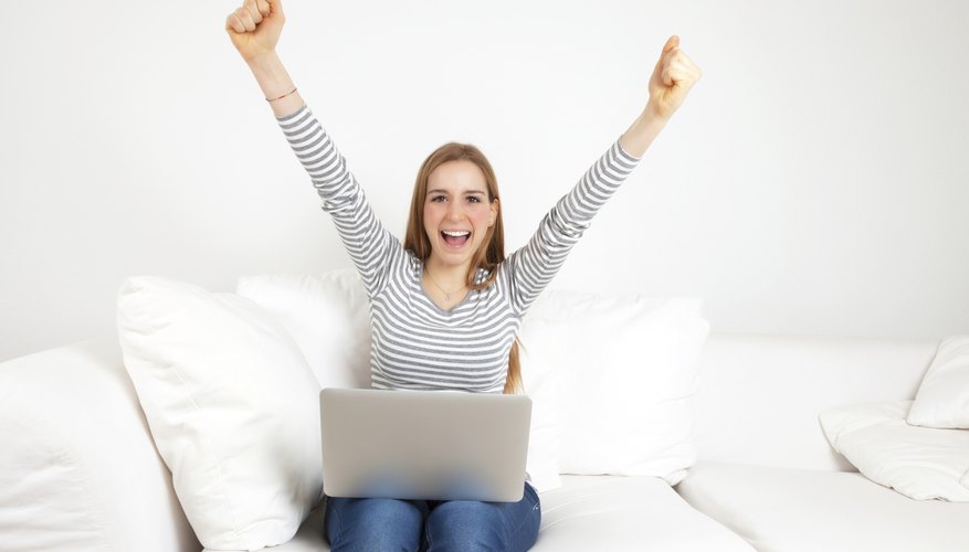 Cheering young woman with notebook on a sofa