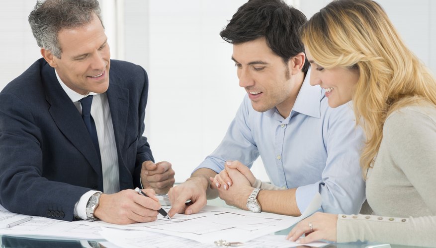 A couple signing documents, sitting next to a mortgage lender