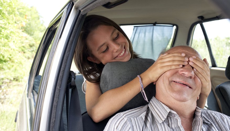 girl putting hands over grandfather's eyes