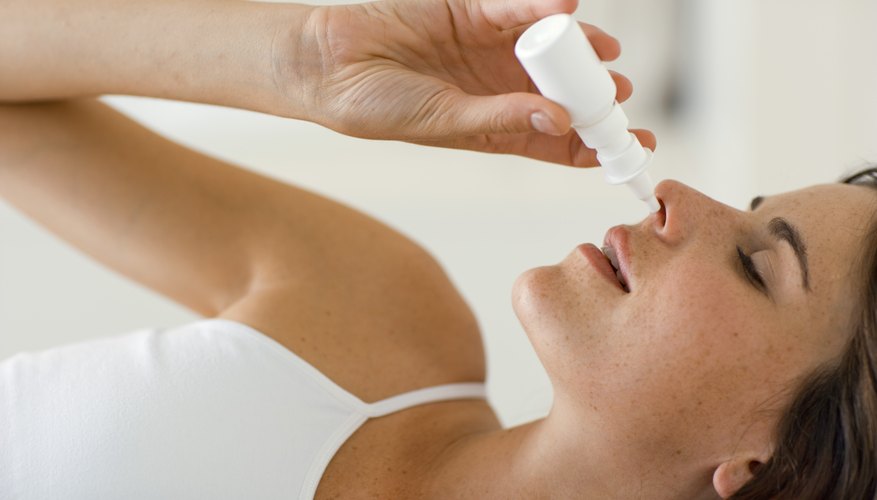 Woman using a nasal spray decongestant Woman using a nasal spray decongestant
