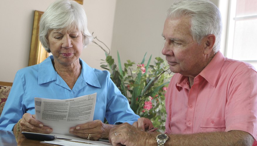 A senior couple reviews paperwork together in their living room