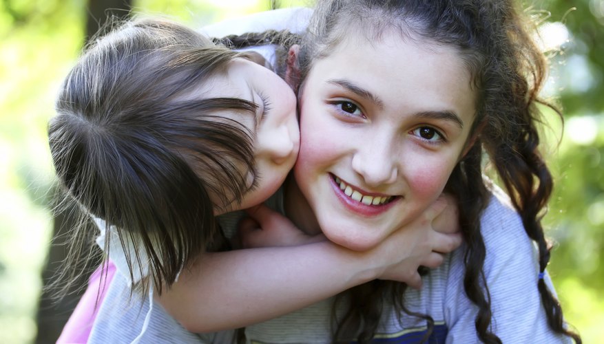 A teenage girl gives a piggyback ride to a younger girl A teenage girl gives a piggyback ride to a younger girl