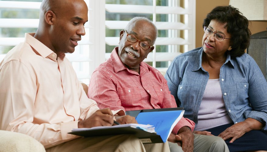 A financial advisor is talking to a senior couple in their home.