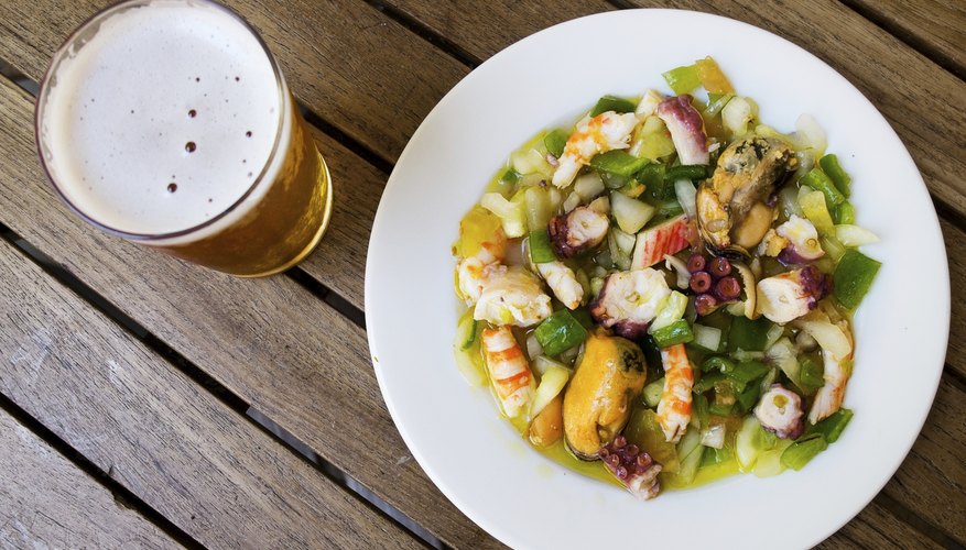 An overhead view of a seafood dish and a pint of beer. An overhead view of a seafood dish and a pint of beer.
