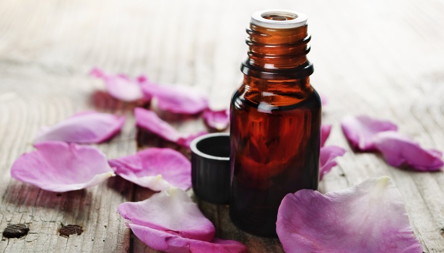 Essential rose oil surrounded by rose petals Essential rose oil surrounded by rose petals