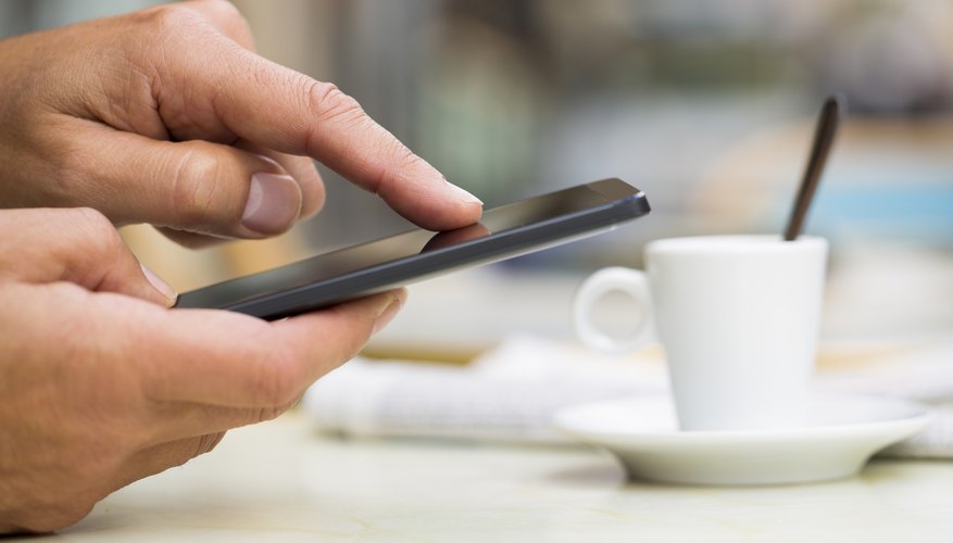 Photo Credit: LDProd/iStock/Getty Images A man using his smart phone on a cafe terrace.