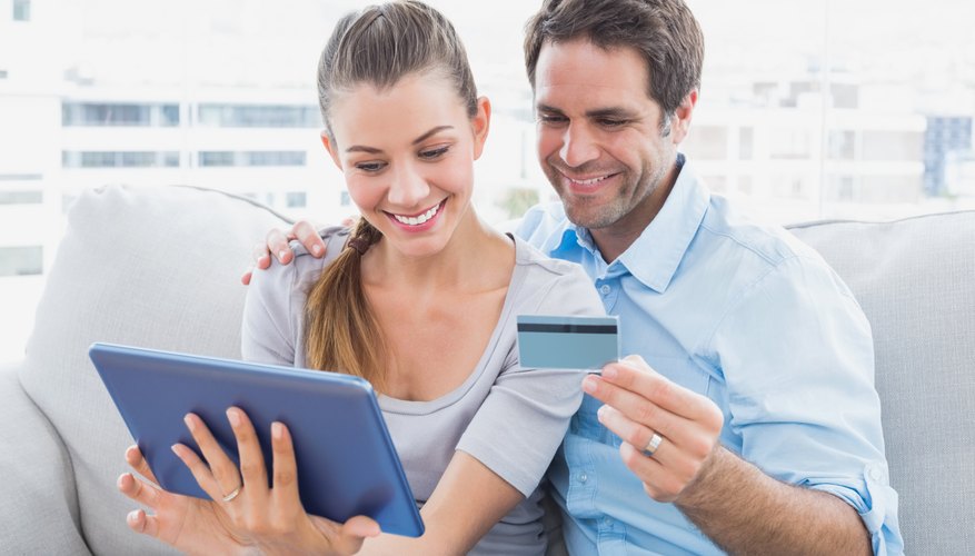 Happy couple relaxing on the couch shopping online with tablet pc