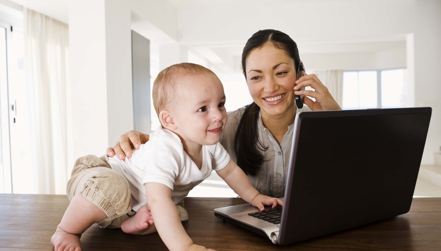 Mother on cell phone and baby looking at laptop computer