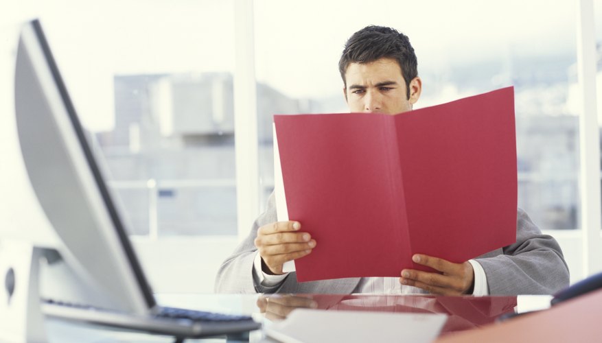 Young businessman at desk looking at folder