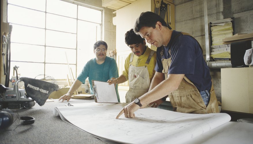 a group of men study building plans