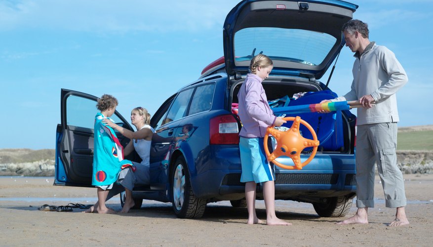 Family unpacking toys from car on beach