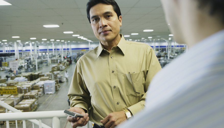 Businessman leaning on railing with warehouse in background