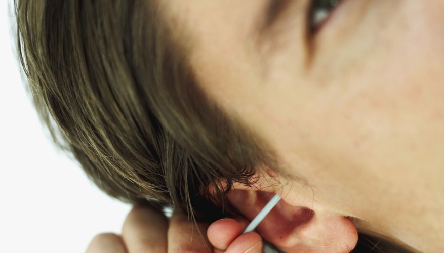 Man cleaning ear with Qtip Man cleaning ear with Qtip