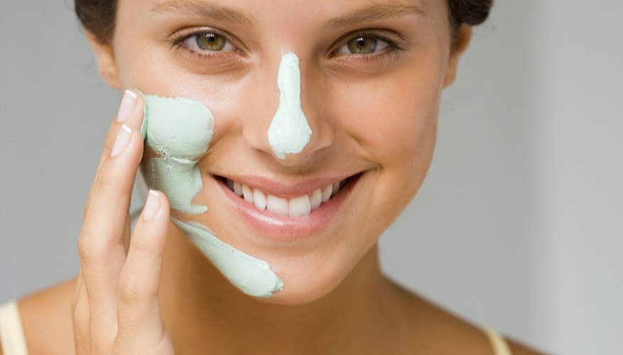 Woman applying clay mask Woman applying clay mask