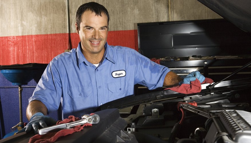 Auto mechanic posing next to car