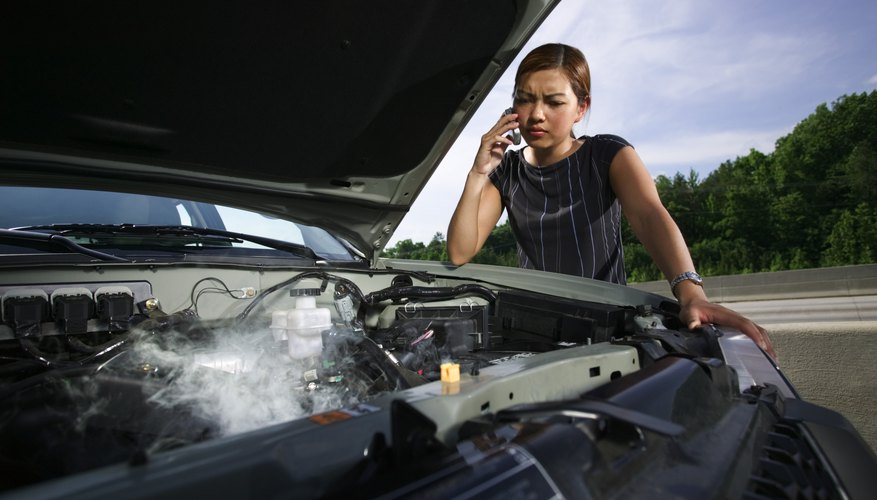 Woman looking at smoking engine while using cell phone
