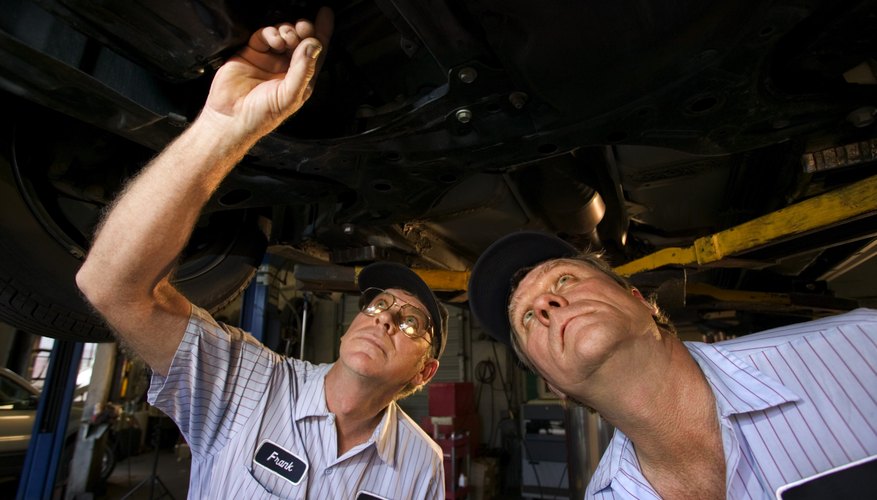 Mechanics looking up under car on lift