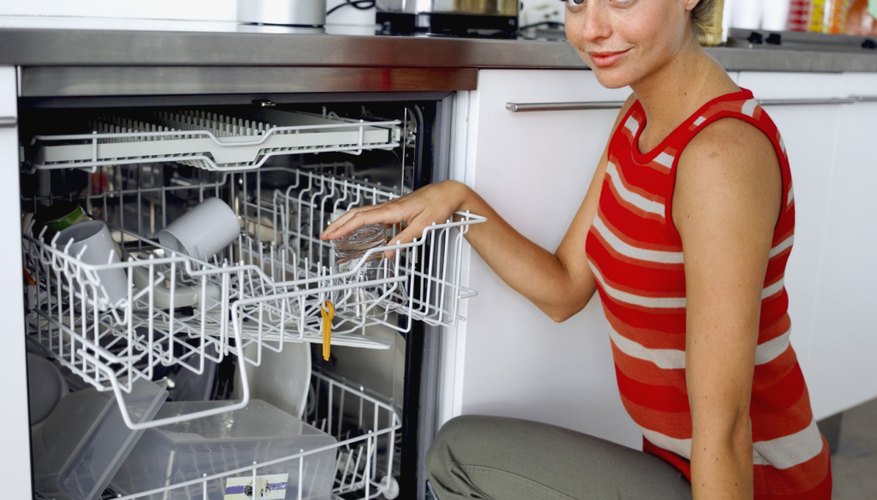 Portrait of a young woman putting dishes in a dishwasher