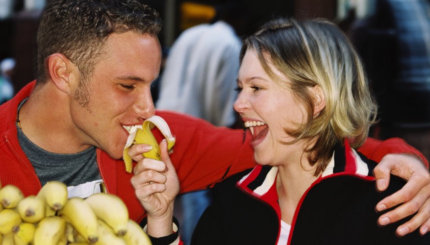 Banana being fed to man at food market stall Banana being fed to man at food market stall