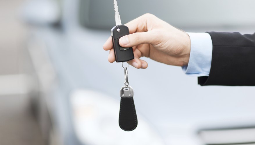 Car salesman holding the key to a new vehicle
