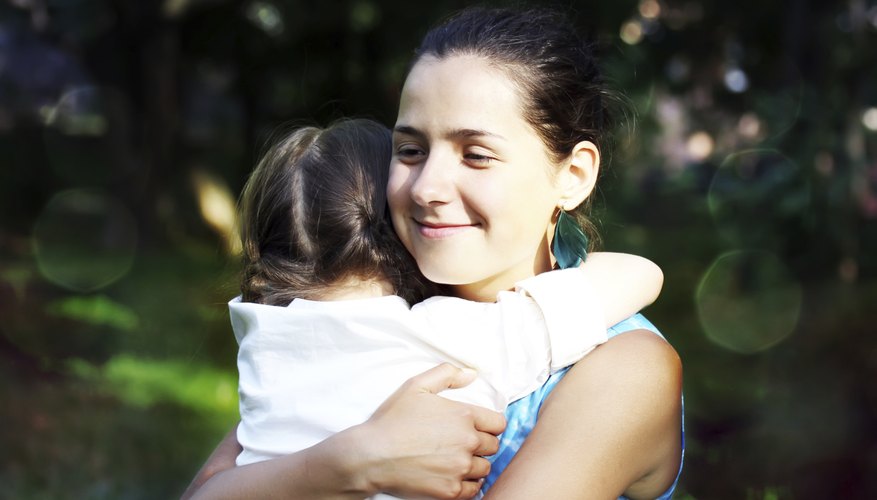 A smiling mother hugging her daughter outside. A smiling mother hugging her daughter outside.