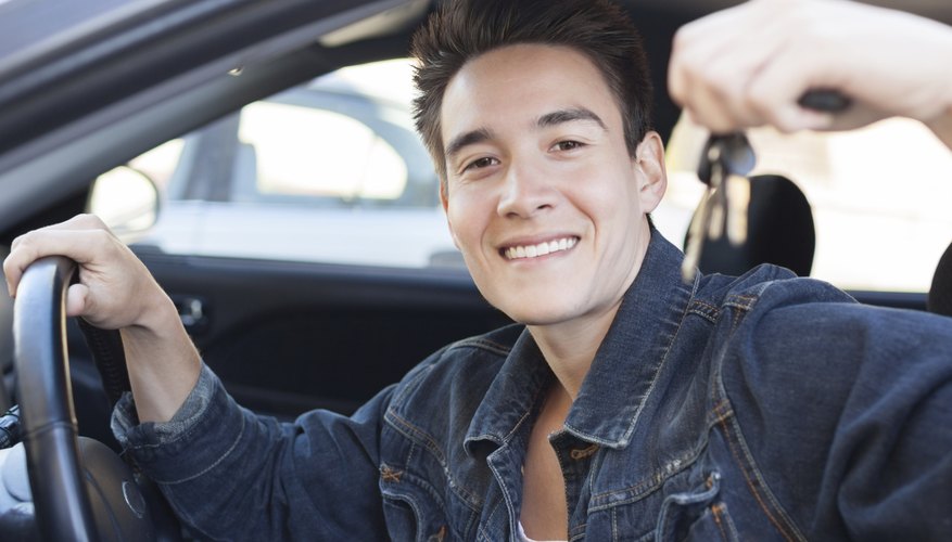A man is sitting in his new car holding keys.