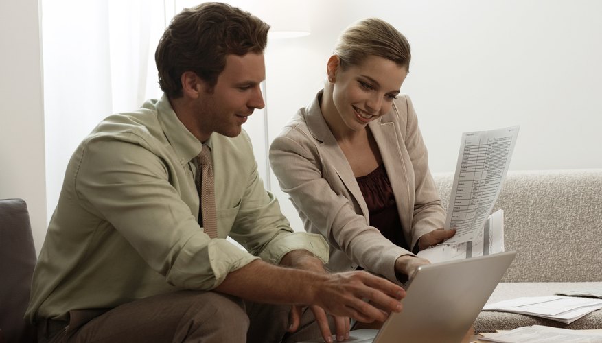 Businessman and businesswoman sitting at table looking at laptop