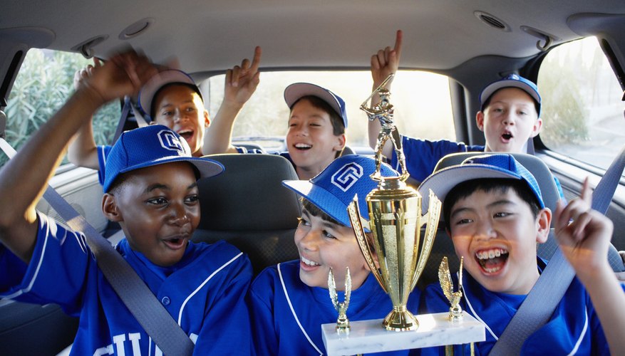 Boys on a little league team celebrate a winning game in a SUV. Boys on a little league team celebrate a winning game in a SUV.