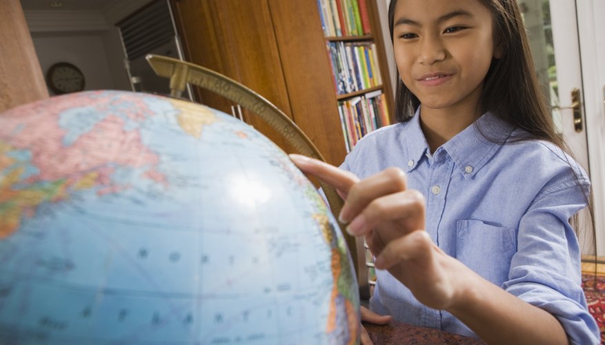 Photo Credit: Jupiterimages/Stockbyte/Getty Images A girl pointing to a globe in the library.
