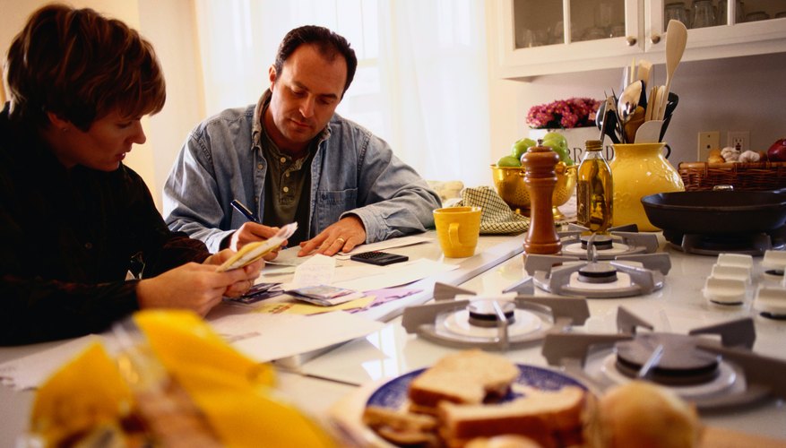 A couple sits at the table analyzing bills and their budget.
