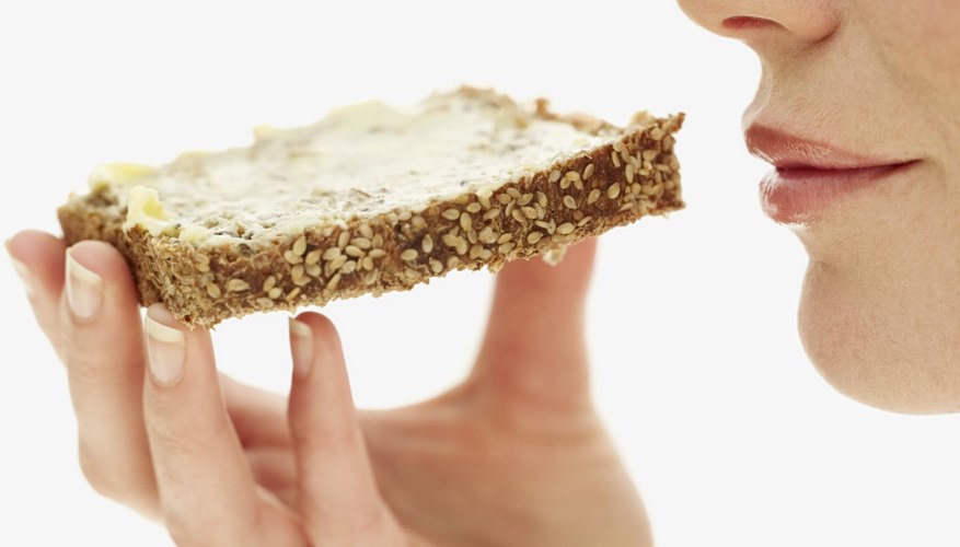 A woman eats a slice of whole grain bread. A woman eats a slice of whole grain bread.
