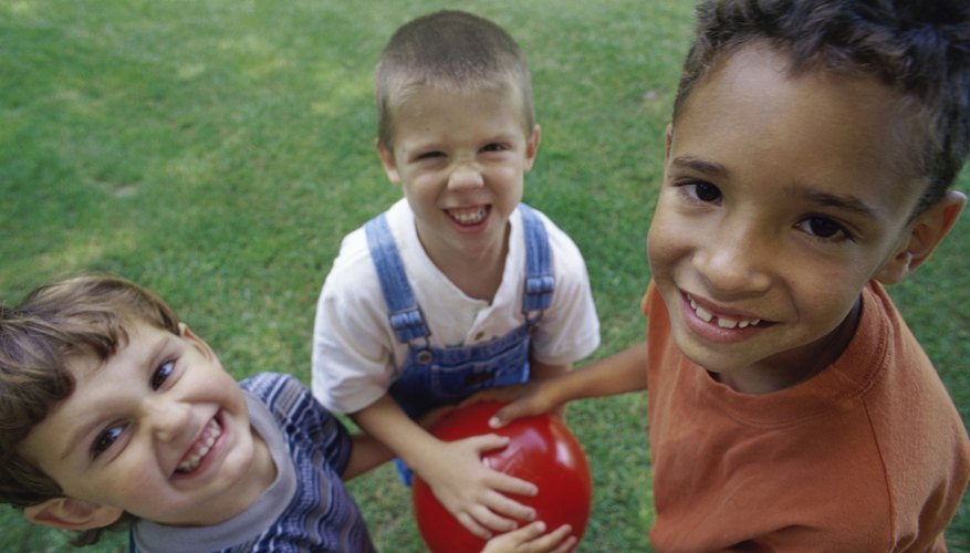 Three boys with hands on one ball outside. Three boys with hands on one ball outside.