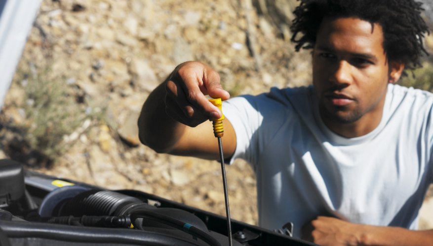 Close-up of young man checking oil level of car with dipstick