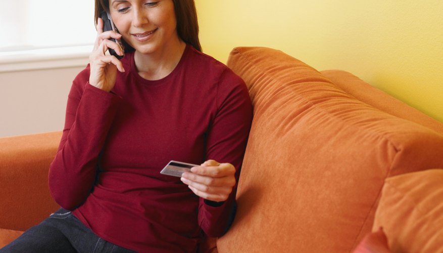 Woman making phonetical while holding up credit card.